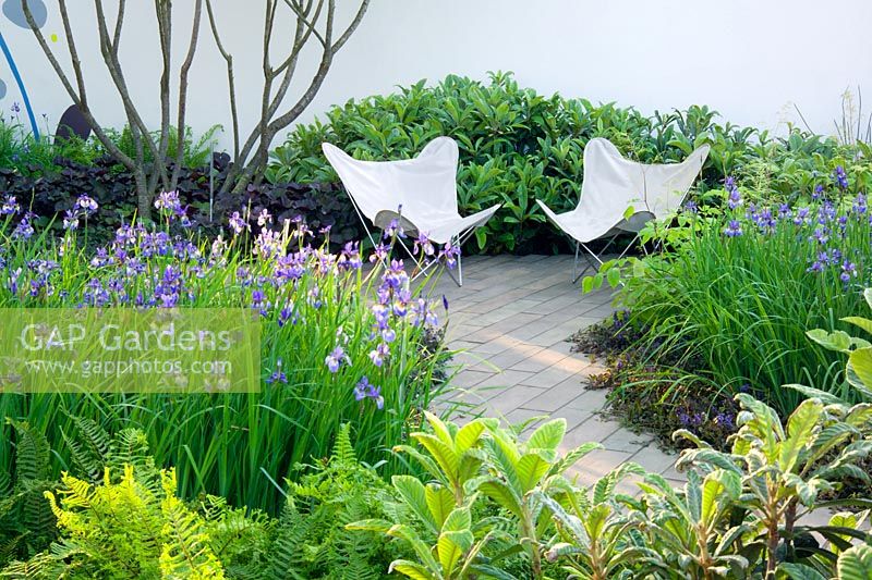 Deux chaises blanches sur pation entourées de plantations vertes luxuriantes dans le jardin Laurent Perrier / Harpers Queen à Chelsea FS 2004