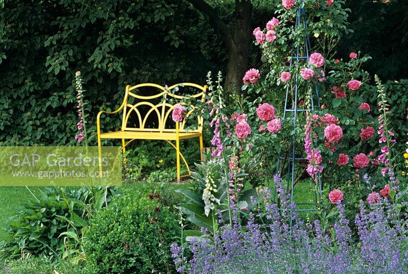 Jardin d'été avec banc en métal jaune et obélisque rose