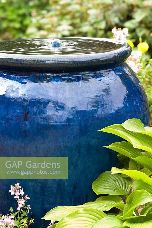 Fontaine à bulles dans un pot en céramique émaillée bleu avec des feuilles d'Hosta.