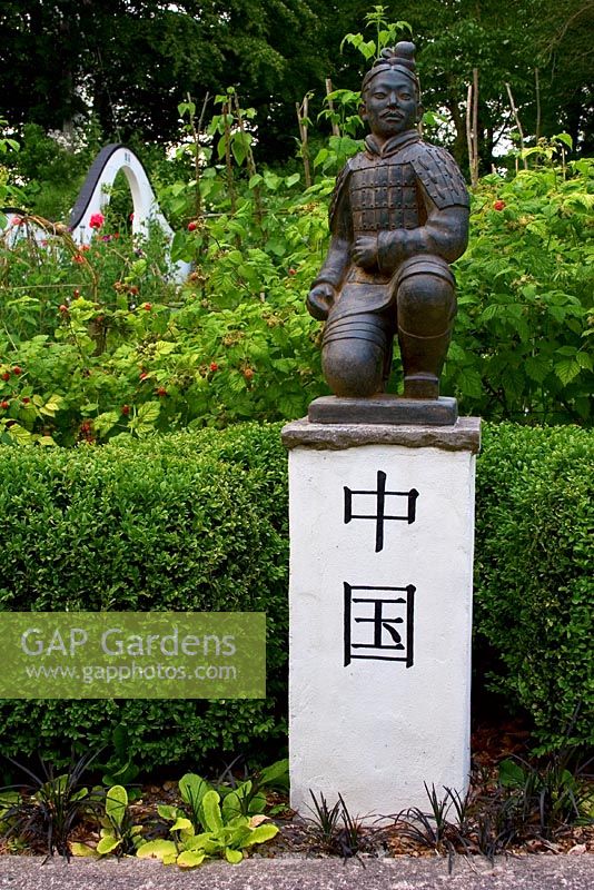 Xi ' un guerrier dans un jardin d'influence chinoise avec haie de buis et moongate derrière - Wiltshire