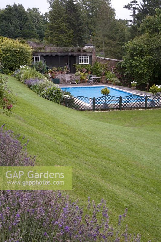 Regardant vers le bas de la pelouse fauchée vers la piscine contenue dans un petit jardin intérieur clôturé.