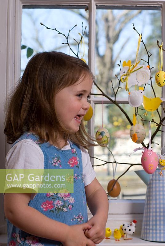 Petite fille suspendue des décorations de Pâques sur un arbre de Pâques à Pâques