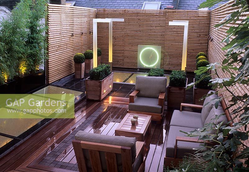 Petit jardin sur toit urbain moderne et contemporain avec terrasse en bois, sièges, éclairage, sphères Buxus en pots - Wilton Place Londres