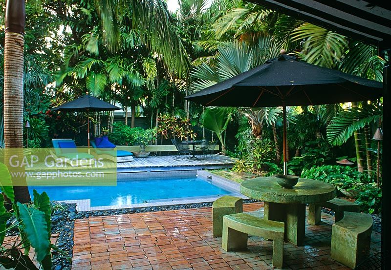 Jardin clos de cour avec piscine, chaises longues, parasols, chaises et tables et plantation tropicale - Key West, États-Unis