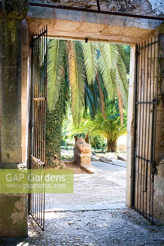 Porte menant à Jardines de Alfabia, Majorque avec palmiers et statue de lion en pierre, sol en galets