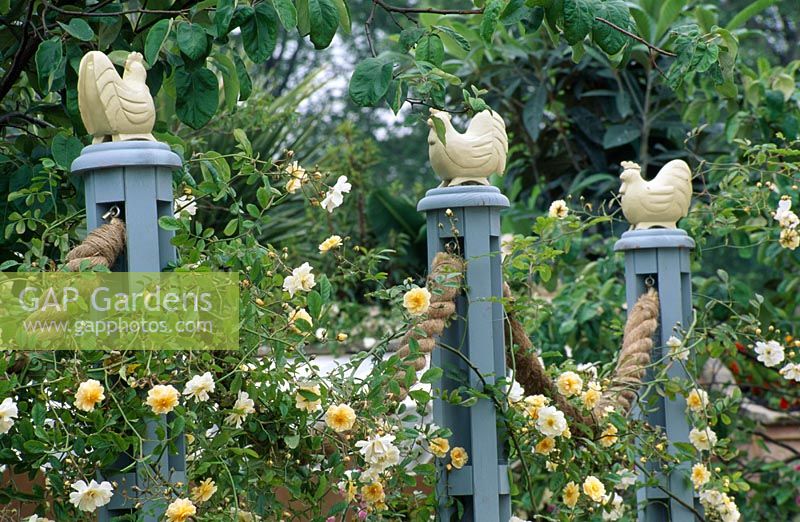 Coqs sculptés et boisés assis au sommet de poteaux reliés par des cordes torsadées - Le jardin DGAA Homelife à Chelsea 1997