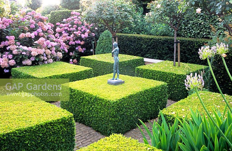 Jardin à la française avec Buxus coupé et petite statue figurative