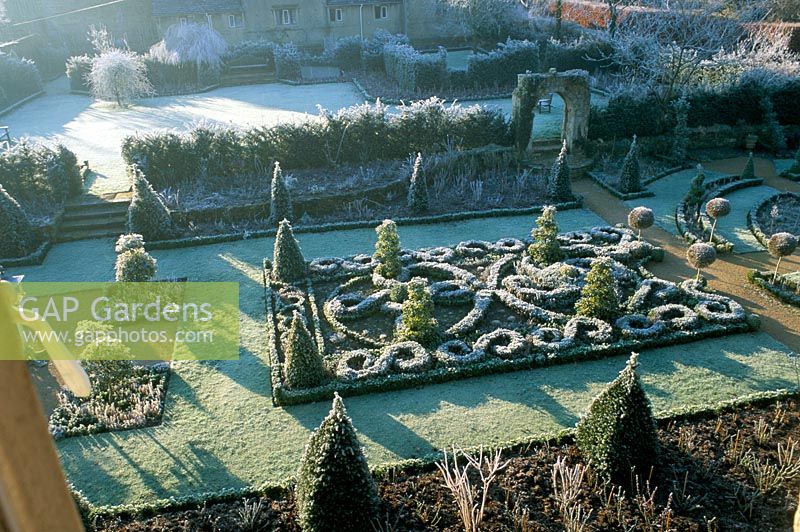 Vue sur le jardin de noeud celtique givré avec topiaire sucette et l'arc saxon - The Abbey House, Wiltshire