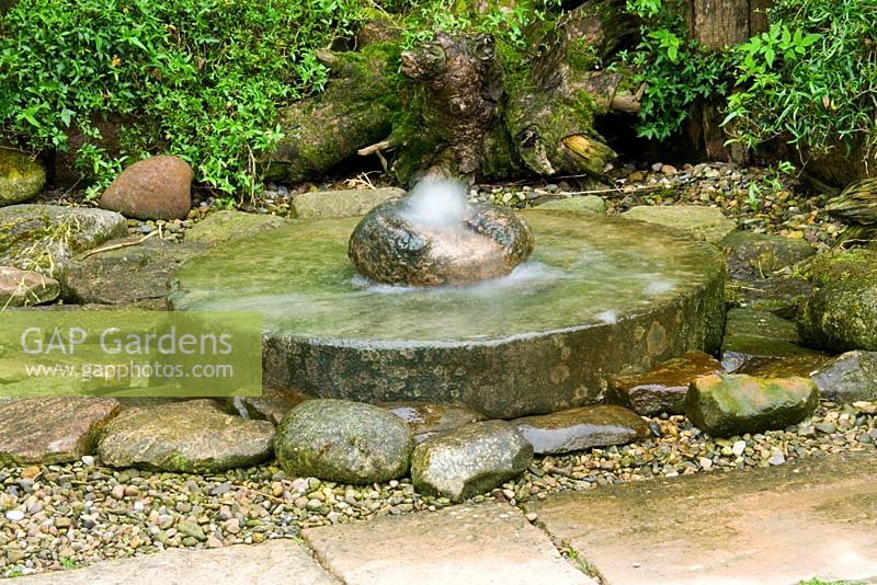 Caractéristique de l'eau de meule entourée de fougères, de gravier et de roches - Hunmanby Grange, Yorkshire