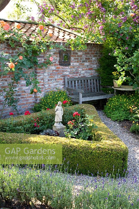 Jardin méditerranéen avec parterre de fleurs triangulaire de Roses, bordé de Buxus et Lavandula en premier plan