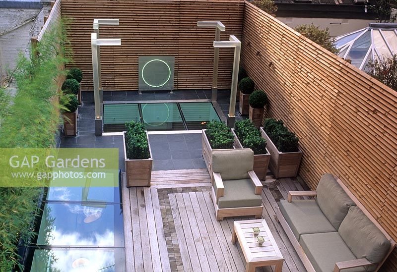 Jardin sur le toit contemporain avec terrasse en bois, sièges, éclairage et sphères Buxus en pots - Wilton Place, Londres