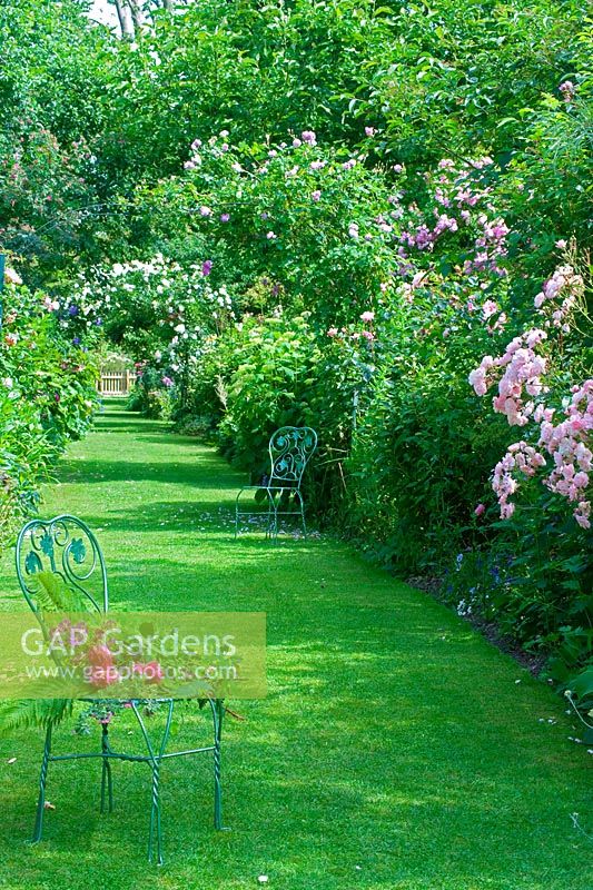 Chemin d'herbe avec sièges métalliques et parterres de fleurs mixtes - Les Jardins d ' Angélique, France