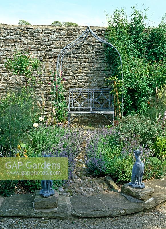 Jardin d'herbes avec statues de lévrier en plomb et siège en métal, Nepeta mussinii, Helianthemum 'Highdown Apricot', Foeniculum vulgare 'Purpureum', Calamintha, Standard Honeysuckle et Rosa 'Agnes' - Lawkland Hall, Yorkshire