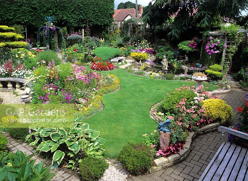 Vue sur pelouse et parterres de fleurs de forme irrégulière avec petit étang - Canonteign, Essex