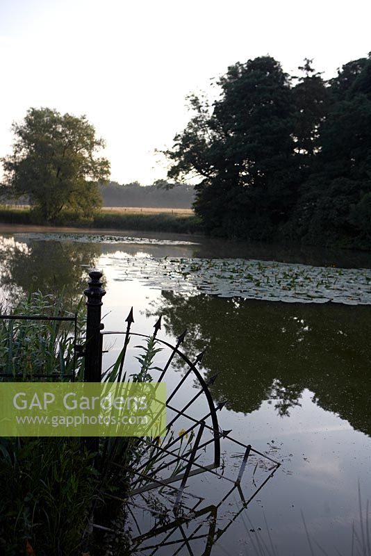 Tôt le matin, vue sur le lac avec des nénuphars et des rampes décoratives en fer - Narborough Hall