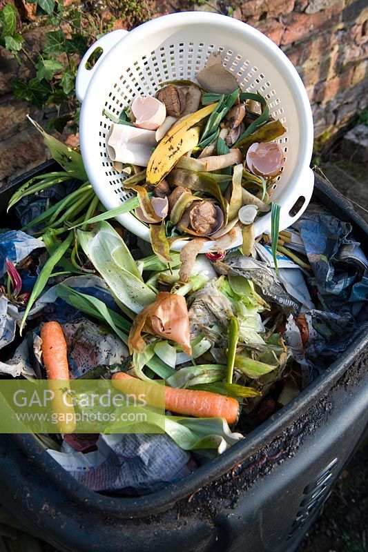 Passoire en plastique avec des déchets alimentaires ajoutés au bac à compost