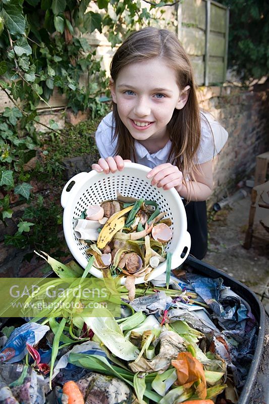 Fille vidant une passoire en plastique avec des déchets alimentaires dans le bac à compost
