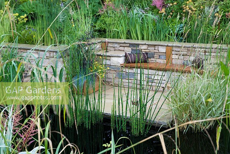 Coin salon en contrebas entouré par un étang avec une plantation marginale au monde du jardin d'eau - Hampton Court Flower Show 2008
