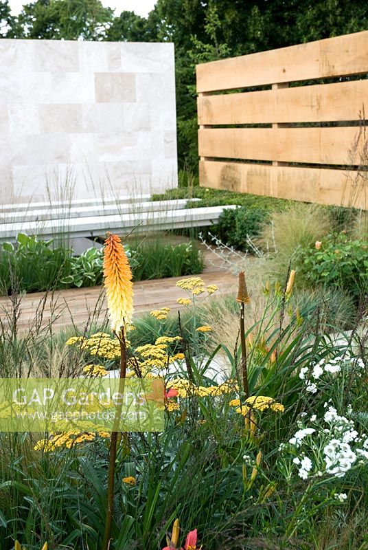 Hemerocallis, Achillea 'Terracotta', Stipa tenuissima et Kniphofia dans The Traveller's Garden avec Bradstone - Hampton Court Flower Show 2008
