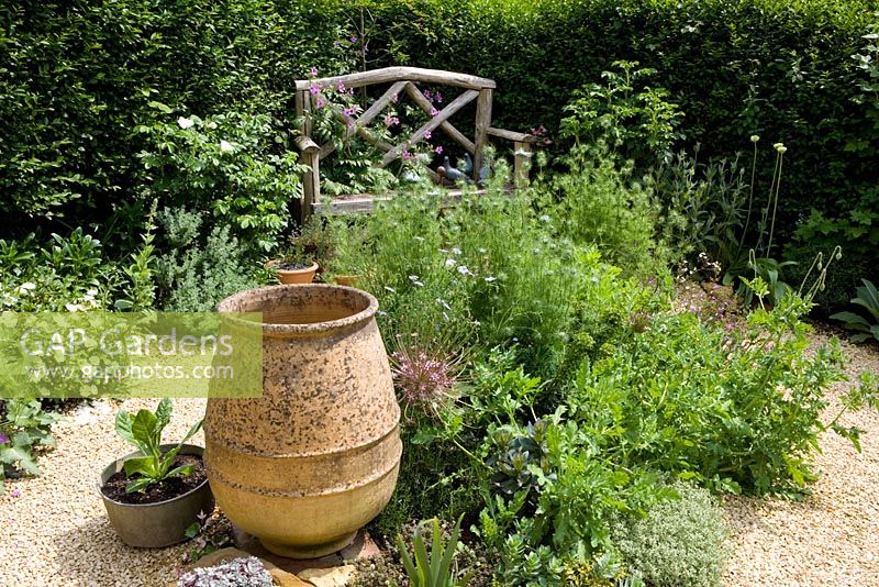 Banc en bois dans la zone de gravier avec une urne en terre cuite vide avec Nigella, Alliums et Geranium plamatum - Eldenhurst