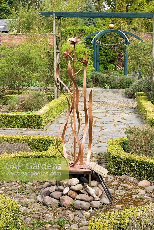 'The Singing Rose 'conçu et réalisé par Cilia West au centre de la roseraie formelle, des bordures Buxus et des sentiers de l'ardoise Westmorland - Poulton Hall, jardin NGS, Cheshire