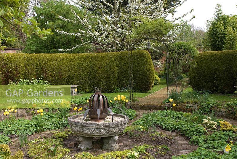 'The Bud 'de Sue Sharples au milieu du jardin circulaire du Golden Bowl avec des chemins et des murs en brique - Poulton Hall, jardin NGS, Cheshire