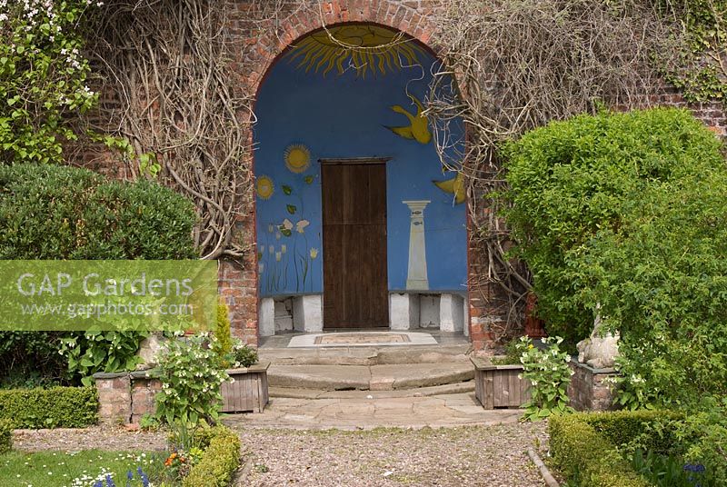 Le Gazebo en forme de dôme, avec porte en bois et murs ornés de motifs, dans le jardin clos - Poulton Hall, NGS garden Cheshire