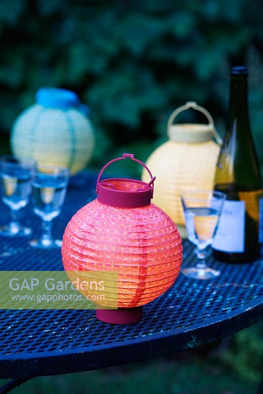 Lanternes colorées et verres sur une table de jardin
