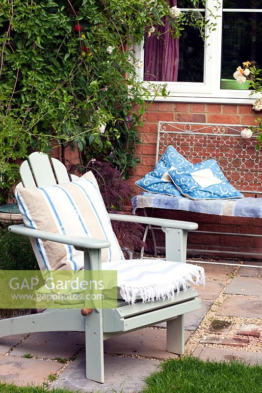 Chaise de jardin Adirondack et banc en métal sur un petit patio dans un jardin urbain