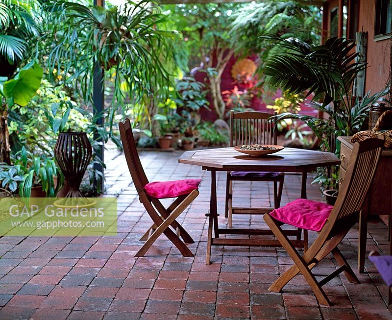 Coin salon avec coussins roses entourés de plantations tropicales