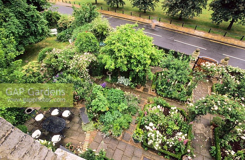 Vue aérienne montrant le jardin à la française en face de la maison avec des allées et des parterres de fleurs avec une plantation mixte dense, des bordures de boîte et de nombreuses pergolas couvertes de roses - New Square, Cambridge
