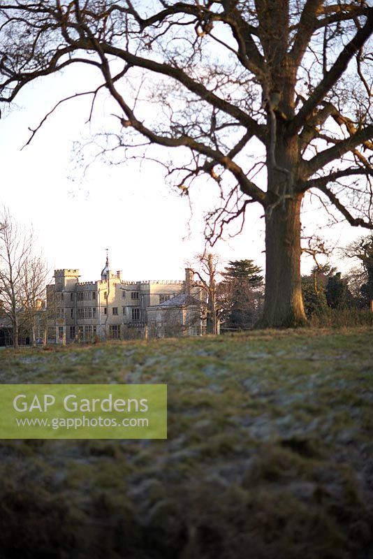 Rousham en hiver. Vue de la maison Rousham attraper le soleil d'hiver à travers champ givré avec arbre à feuilles caduques mature.