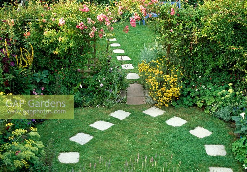 Jardin arrière de banlieue, Lorne Road, Dorcester, Dorset NGS. Juillet. Vue sur jardin avec Rosa 'Dorothy Perkins' sur arch