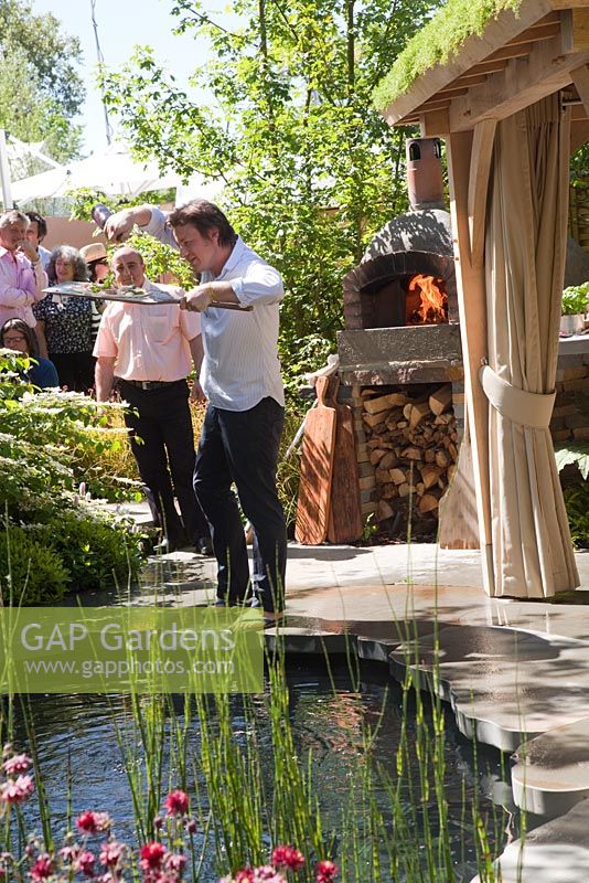 Cuisine de Jamie Oliver. Four en argile à côté d'un bassin profond et d'un coin salon couvert avec toit vert. Jardin de la Children's Society, lauréat de la médaille d'or, RHS Chelsea Flower Show 2010