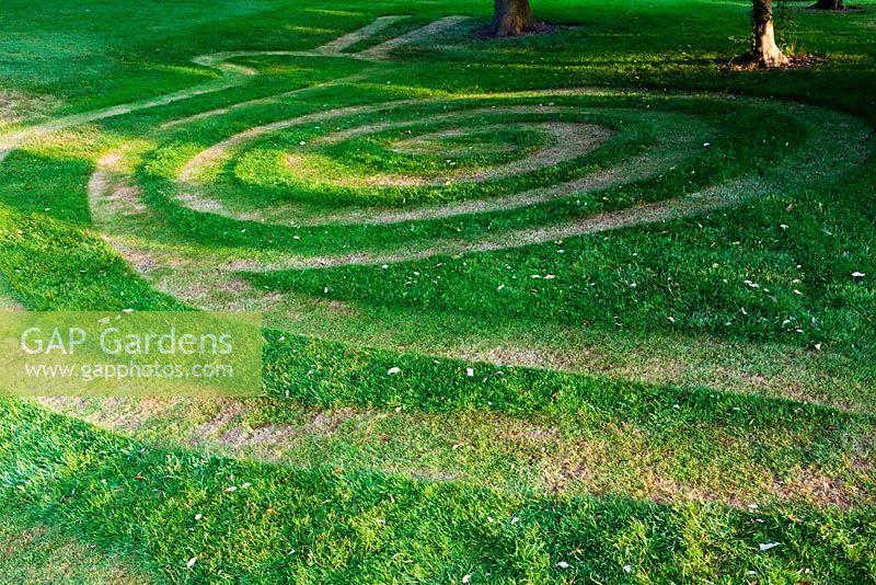 Conception d'escargot coupée en herbe dans la zone boisée avant. Mathern House, Mathern, Monmouthshire, Pays de Galles. Début juin. Ouverture du jardin pour le programme des jardins nationaux.