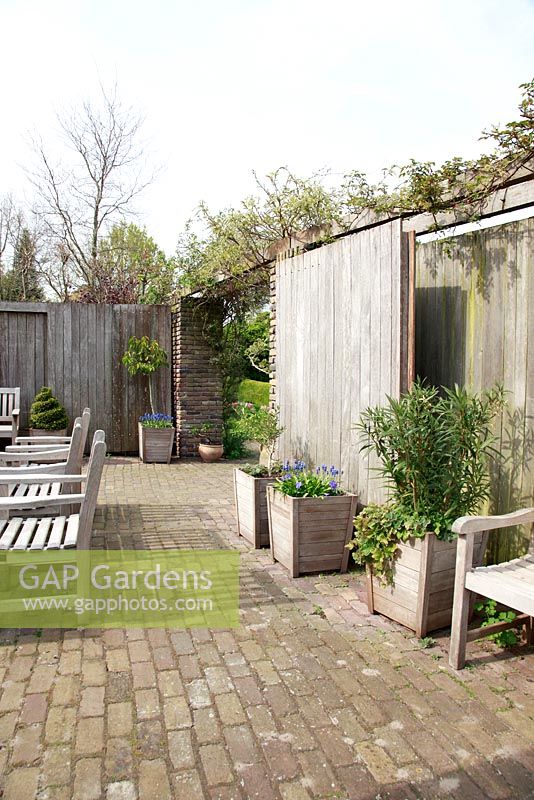 Terrasse avec portes en bois pouvant se fermer pour servir de brise-vent. Jardin de printemps avec la plantation de bulbes spéciaux - Jankslooster, Geke Rook, Hollande