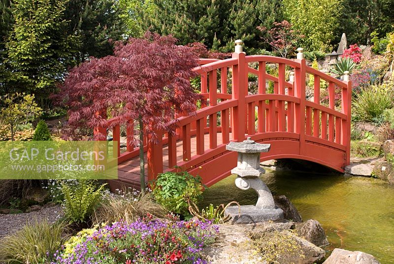 Pont rouge sur la piscine menant à la rocaille dans le jardin japonais à Mount Pleasant Garden, Kelsall, Cheshire