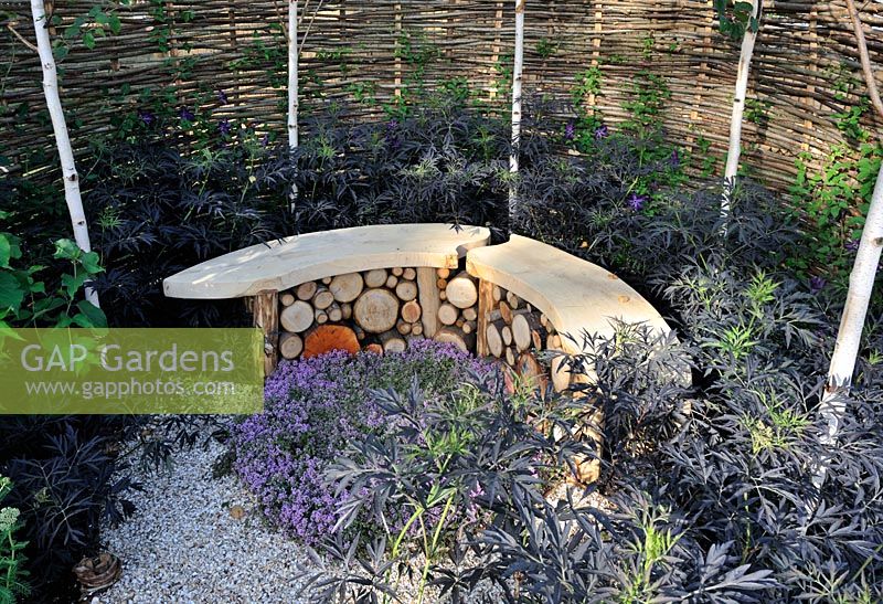 Banc en pierre courbée et en bois entouré d'une clôture en saule. 'It's Only Natural' - Médaillé d'argent doré - RHS Hampton Court Flower Show 2010