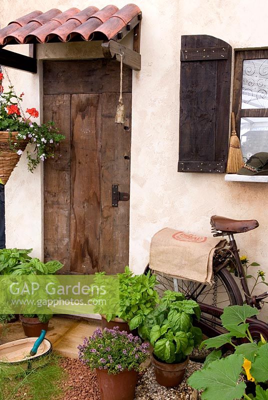 Pots de basilic et de thym à la porte arrière du chalet méditerranéen rustique, avec panier suspendu, trug et vieux vélo - Graines d'Italie, RHS Hampton Court Flower Show 2010