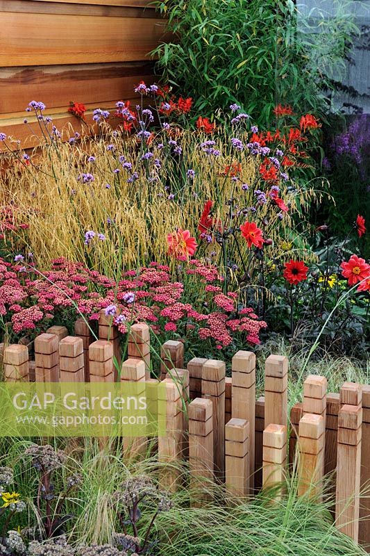 Verveine bonariensis, Achillia 'Red Velvet' avec Miscanthus, souches de bois décoratives comme mur de séparation bas - RHS Tatton Park Flower Show 2010