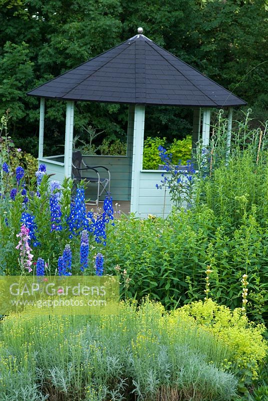 Maison d'été octogonale avec parterre de plantes vivaces adjacentes, y compris Delphinium, Alchemilla, Echinops et Santolina à Southfield, Belper, Debyshire. Ouverture du jardin pour le programme des jardins nationaux