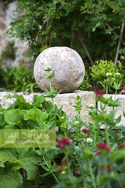 Fleuron en pierre sur mur en pierre sèche avec Centranthus ruber - Valériane - Jardin de la Louve, Provence, France