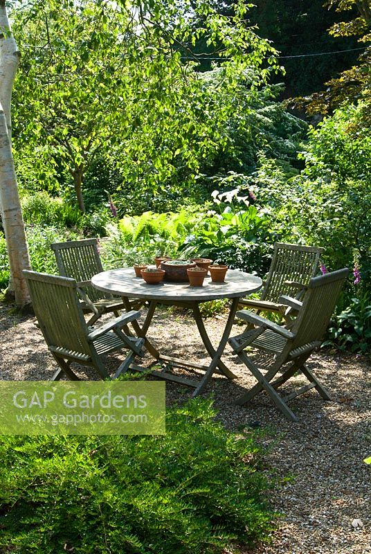 Table et chaises en bois dans le jardin boisé devant, juin. Sandhill Farm House, Hampshire.