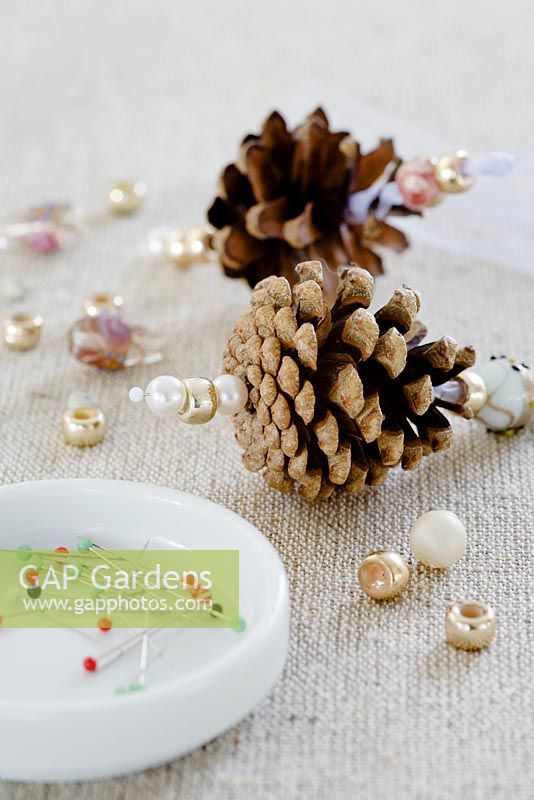 Faire des décorations de pomme de pin avec des perles - ÉTAPE 7. Enfilez 2 ou 3 perles sur une épingle et collez-la solidement au fond de la pomme de pin