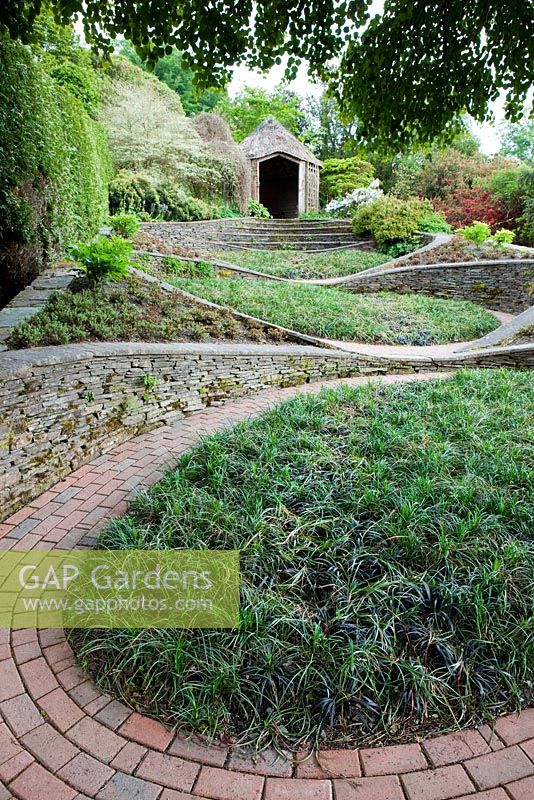 Le 'Jardin des Ovales' aux murs courbes et chemin. La Garden House, Devon.