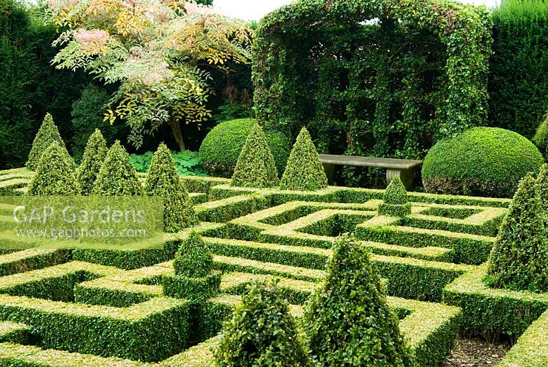 Hedera - Gazebo en forme de port-cullis recouvert de lierre au bout du jardin de noeuds de Buxus coupé - Boîte. Bourton House, Bourton-on-the-Hill, Moreton-in-Marsh, Glos, Royaume-Uni