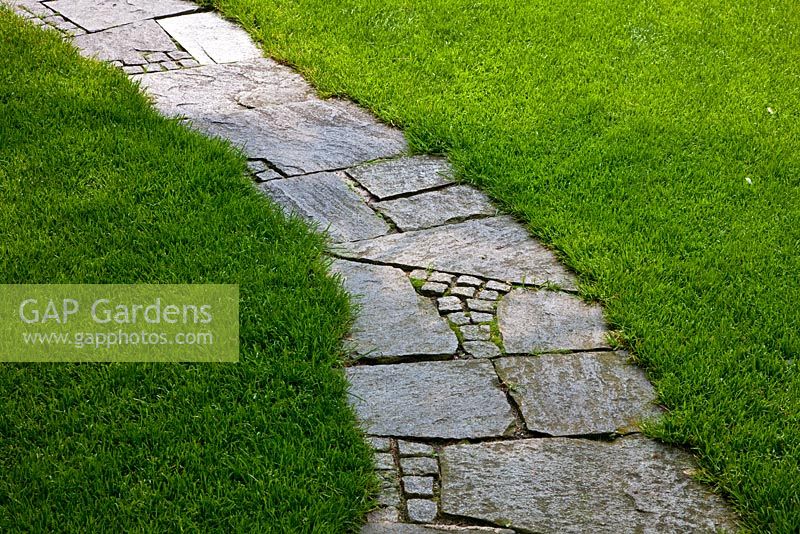 Un chemin pavé de dalles et de granit serpentant sur une pelouse