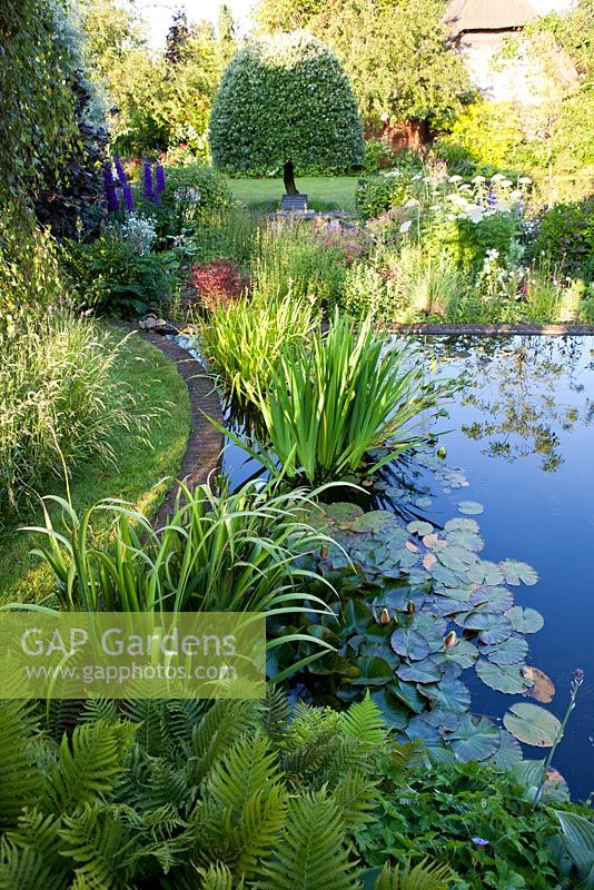 Jardin d'été, grand étang formel entouré de plantations informelles - The Corner House, Wiltshire.