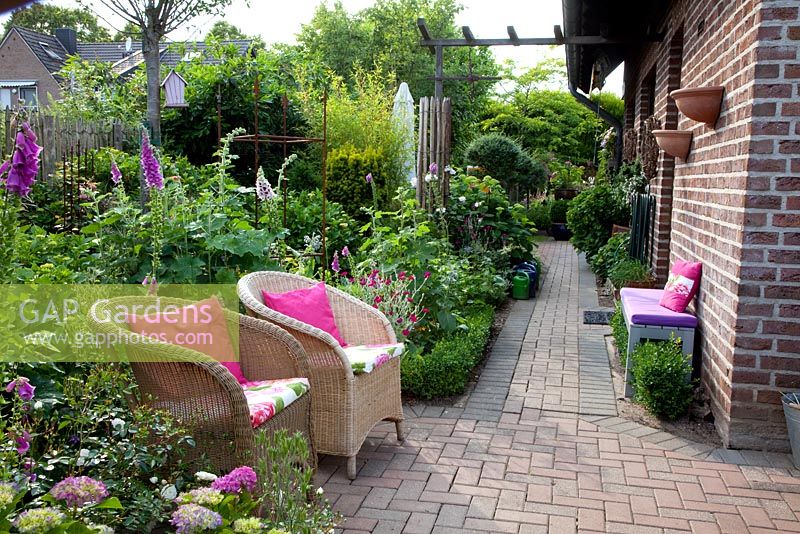 Petit jardin de ville avec des chaises en osier entouré de Digitalis - Foxgloves et Hortensia - Scheper Town Garden