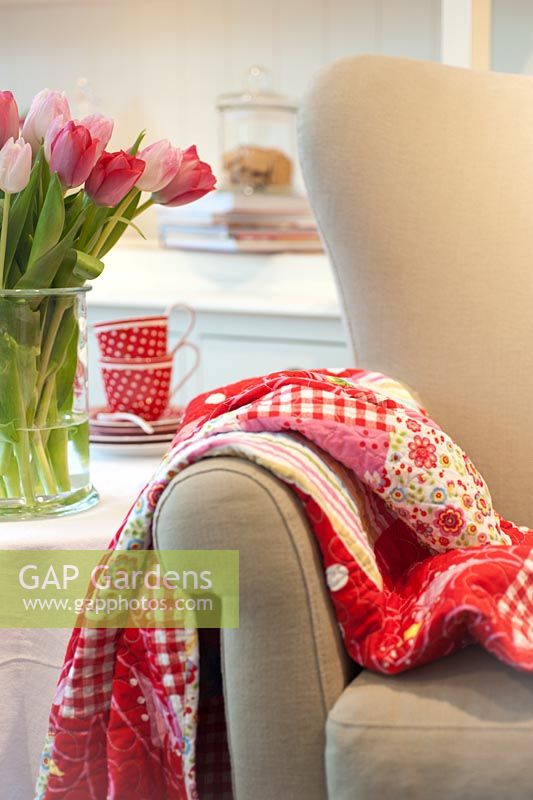 Tulipes rouges et roses dans un vase en verre à côté du fauteuil